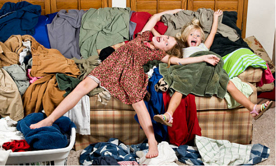 Cluttered living room with clothes and ironing board visible