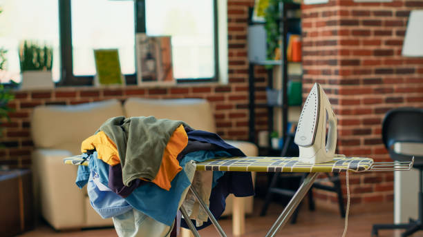 Ironing Board and the Formation of Clothing Aesthetic Standards 1 A neat ironing board with an iron and a pile of clothes ready for ironing.